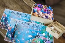 Load image into Gallery viewer, Under the Sea "AB-Seas" Mat with Letter Seashells and a treasure chest filled with shells for placeholders.
