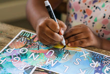 Load image into Gallery viewer, Student using the included dry-erase pen on the reusable Under the Sea "AB-Seas" Mat.